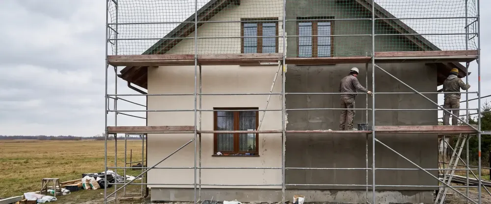 Elewacja domu piętrowego w trakcie prac, część ściany w tynku wykończeniowym, część w warstwie zbrojącej