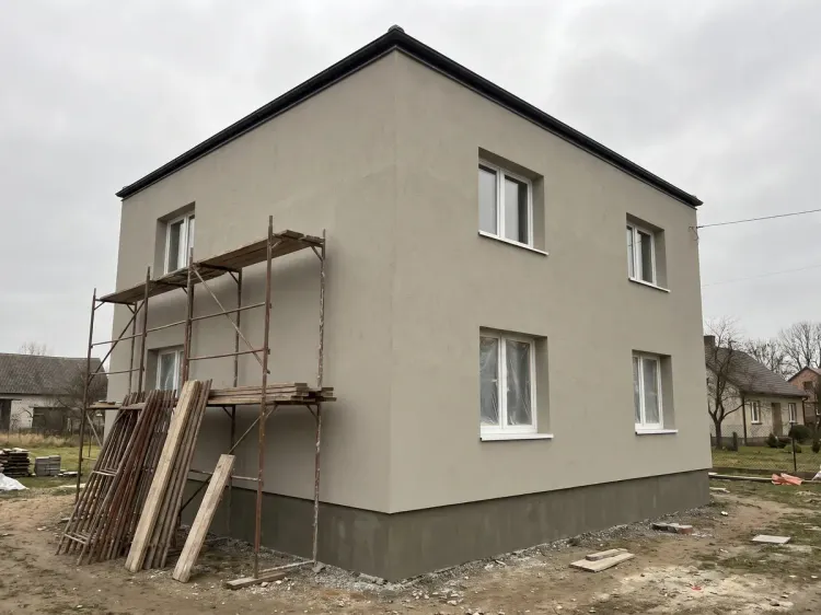 Budynek piętrowy po renowacji elewacji, jasnoszary tynk i ciemniejszy cokół