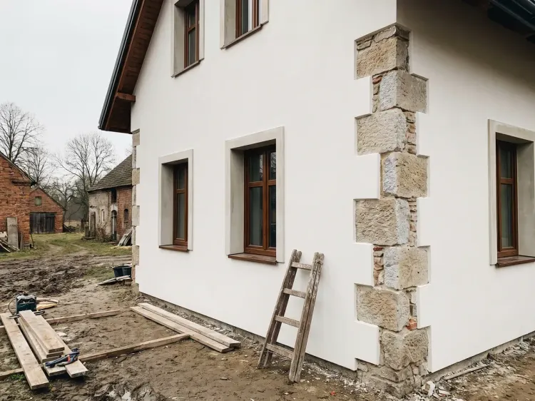 Odnowiona elewacja starszego domu, gładki biały tynk i naprawione ościeża