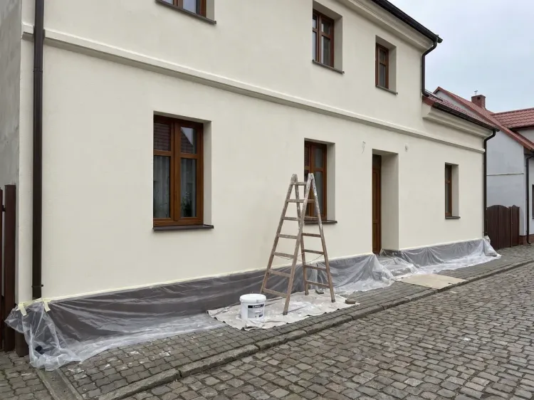 Elewacja pomalowana na jasny kremowy odcień, drabina przy ścianie