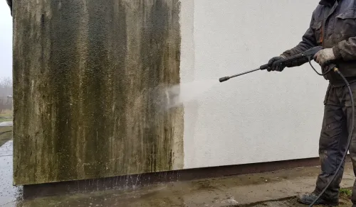 Ściana domu w trakcie mycia ciśnieniowego, ostra granica między brudną a czystą powierzchnią